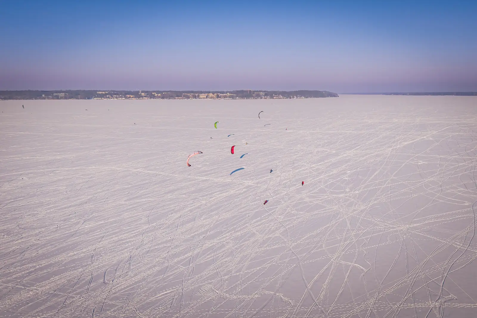 Tientallen kites en sporen op een bevroren, besneeuwd meer