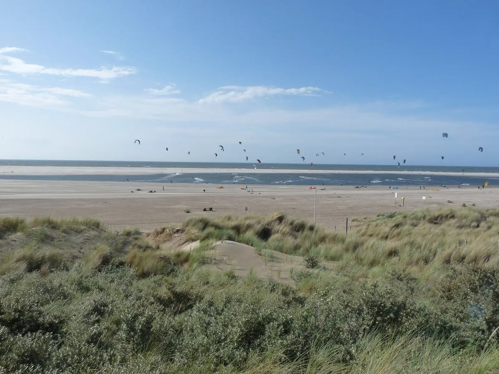 De lagune van de Zandmotor vanaf het duin, met een rij kites boven de zandbank